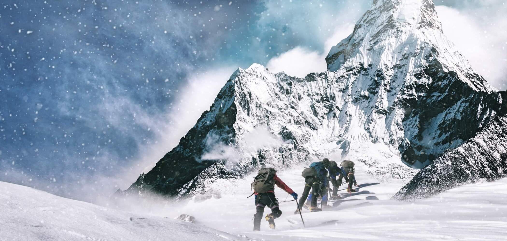 Climbers scaling a rugged alpine ridge in high-altitude conditions.