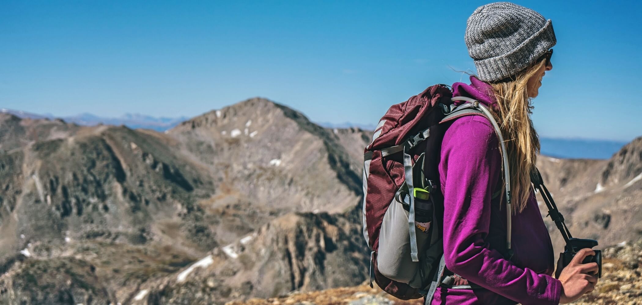 Hiker walking along a mountain trail with expansive views.