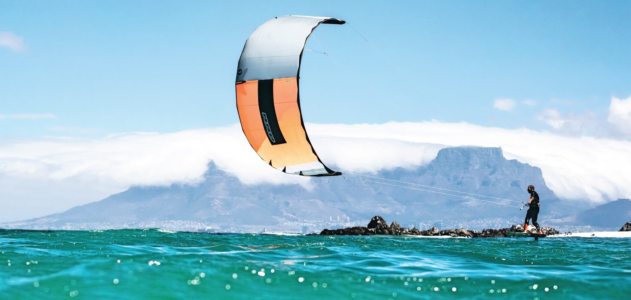  Kitesurfer gliding over turquoise water on a remote beach.
