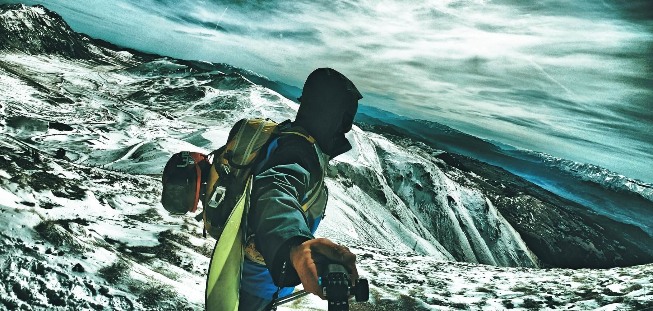 Snowboarder descending a snowy alpine slope with fresh powder.